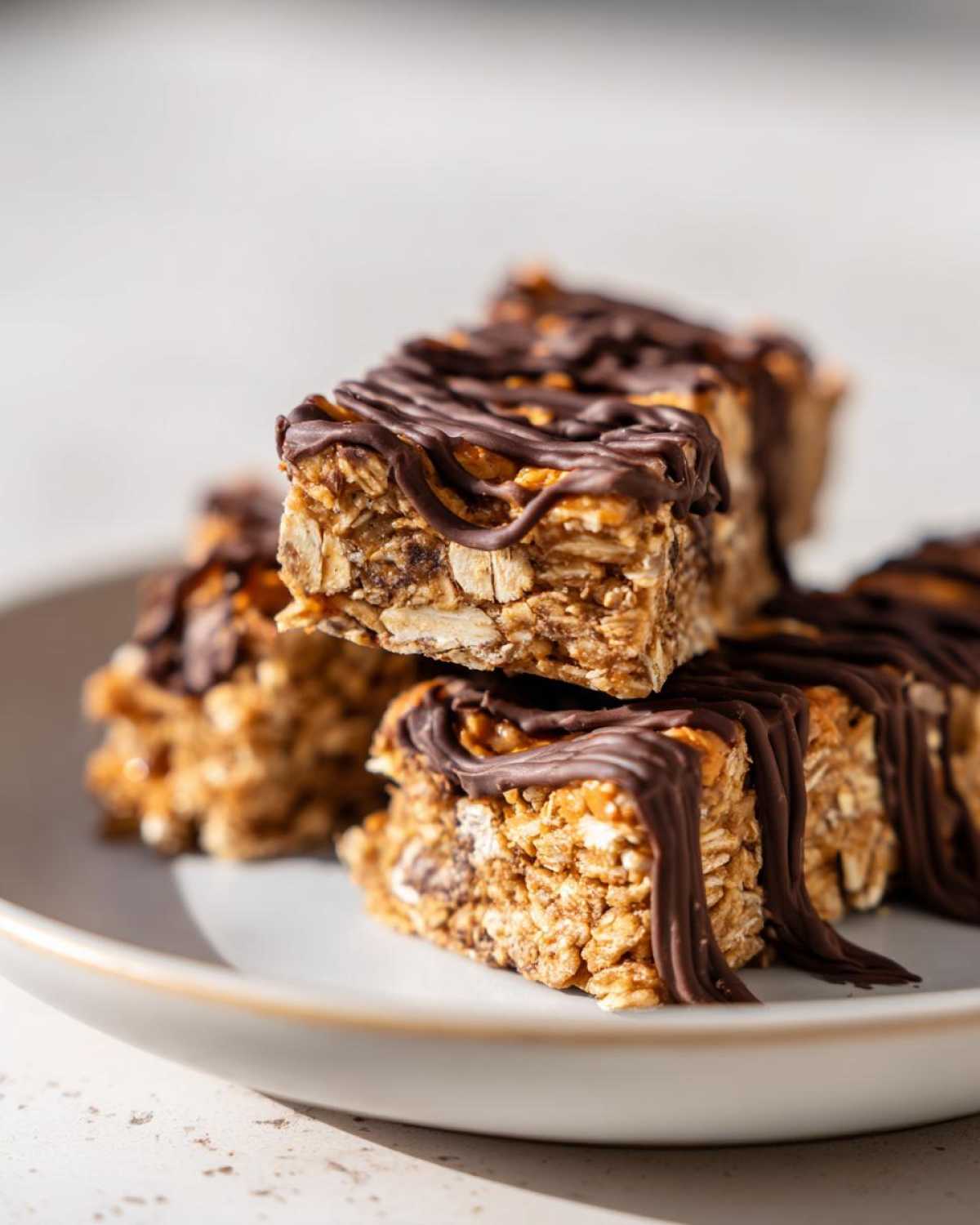 Close-up of stacked, homemade protein bars drizzled generously with melted dark chocolate.