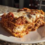 A close-up, sunlit serving of amazing 1-layer lasagna showing rich meat sauce and melted cheese.