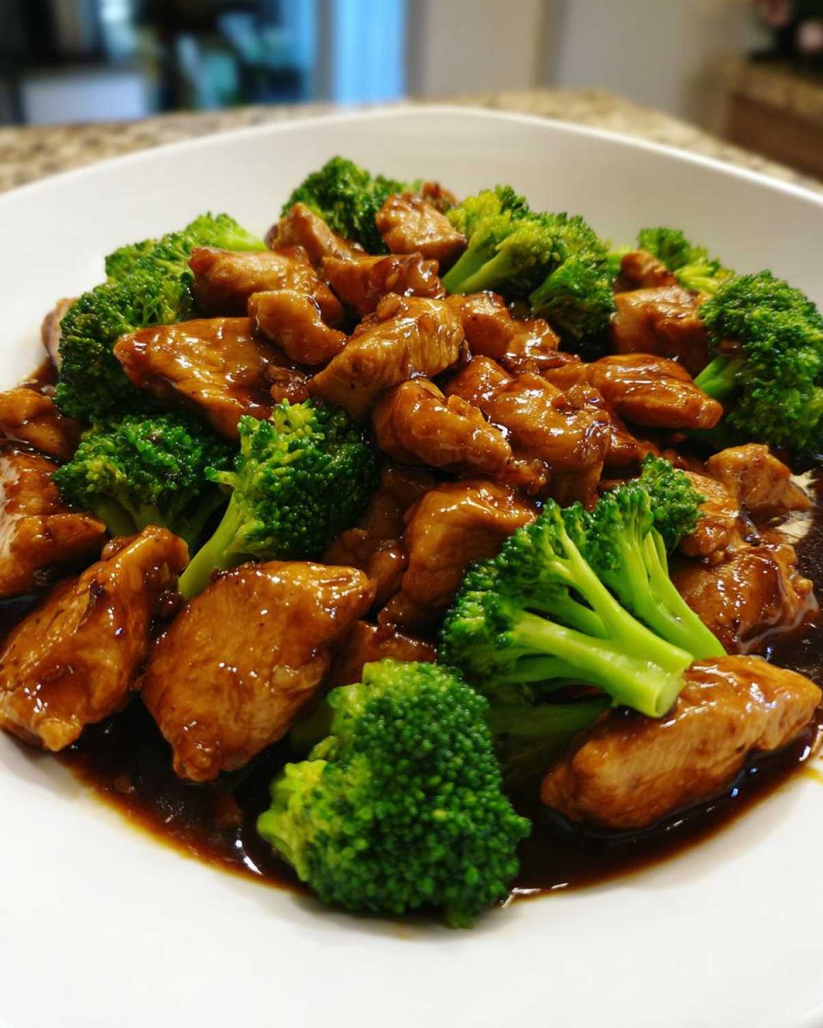 Close-up of tender pieces of chicken and bright green broccoli florets coated in a rich brown sauce, featuring chicken and broccoli.