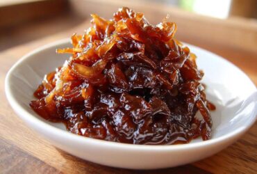 A close-up of rich, dark brown caramelized onions piled high in a small white bowl.