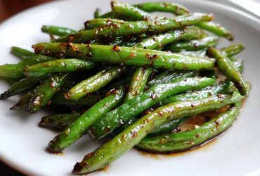 Close-up of vibrant green beans coated in a savory garlic sauce, ready to serve.