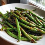 Close-up of vibrant green beans coated in a rich, dark chinese green beans with garlic sauce.