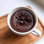 Overhead view of a rich, dark chocolate chip mug cake inside a white mug.
