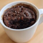 Close-up of a freshly baked chocolate mug cake topped with melted chocolate chips.