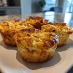 Four golden-brown cottage cheese egg cups starbucks style served on a rectangular white plate.