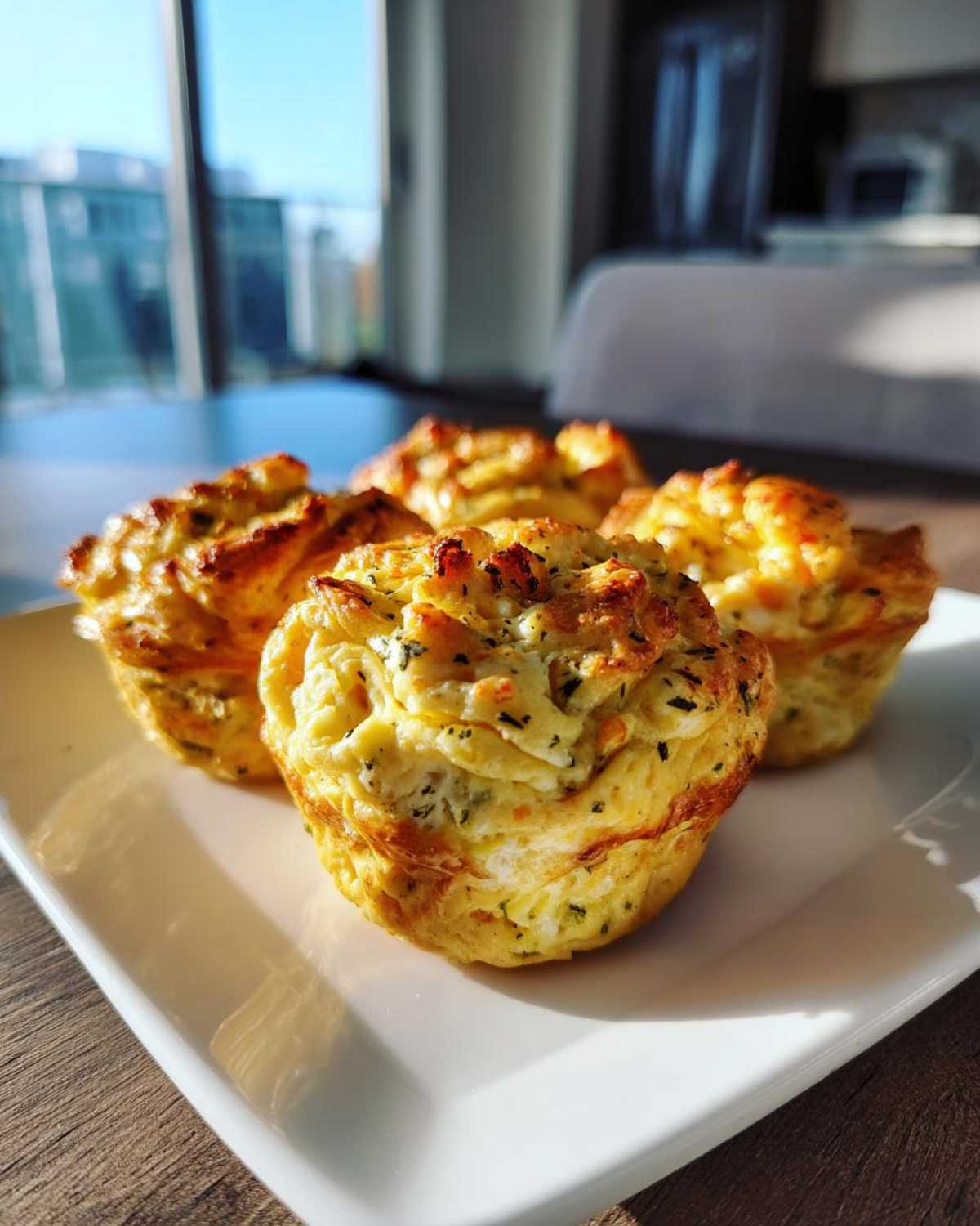 Four golden brown cottage cheese egg cups starbucks style served on a white rectangular plate.