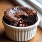 Close-up of a warm Cottage Cheese Microwave Brownie with a molten chocolate center spilling out of a white ramekin.