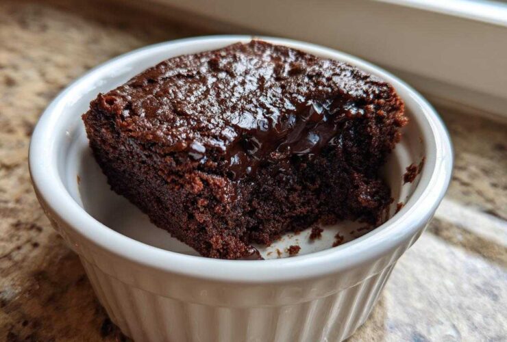 A rich, dark chocolate Cottage Cheese Microwave Brownie served warm in a white fluted ramekin.