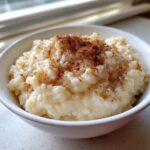 Close-up of a bowl of creamy rice pudding generously sprinkled with ground cinnamon.