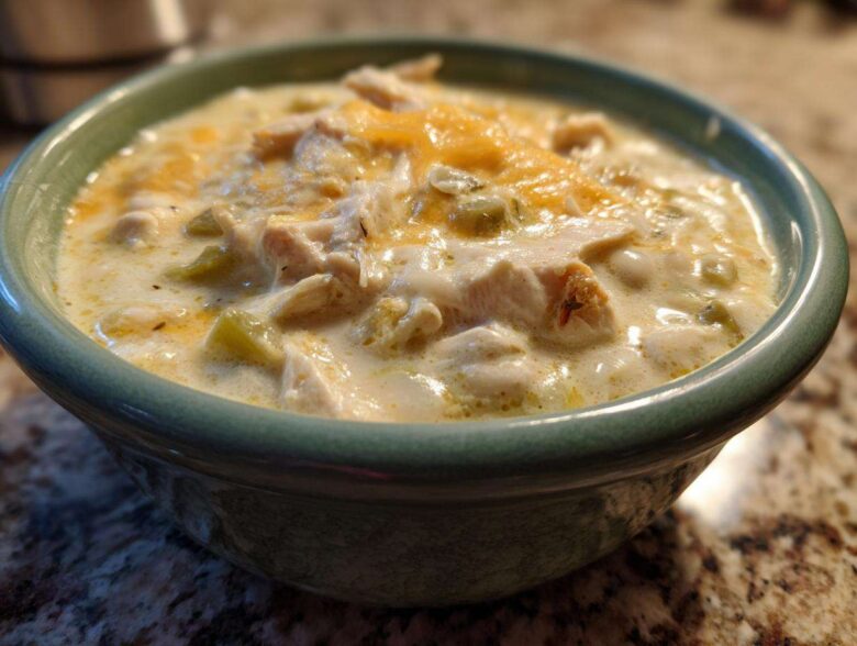 Close-up of a bowl of creamy crockpot white chicken chili topped with melted cheese.