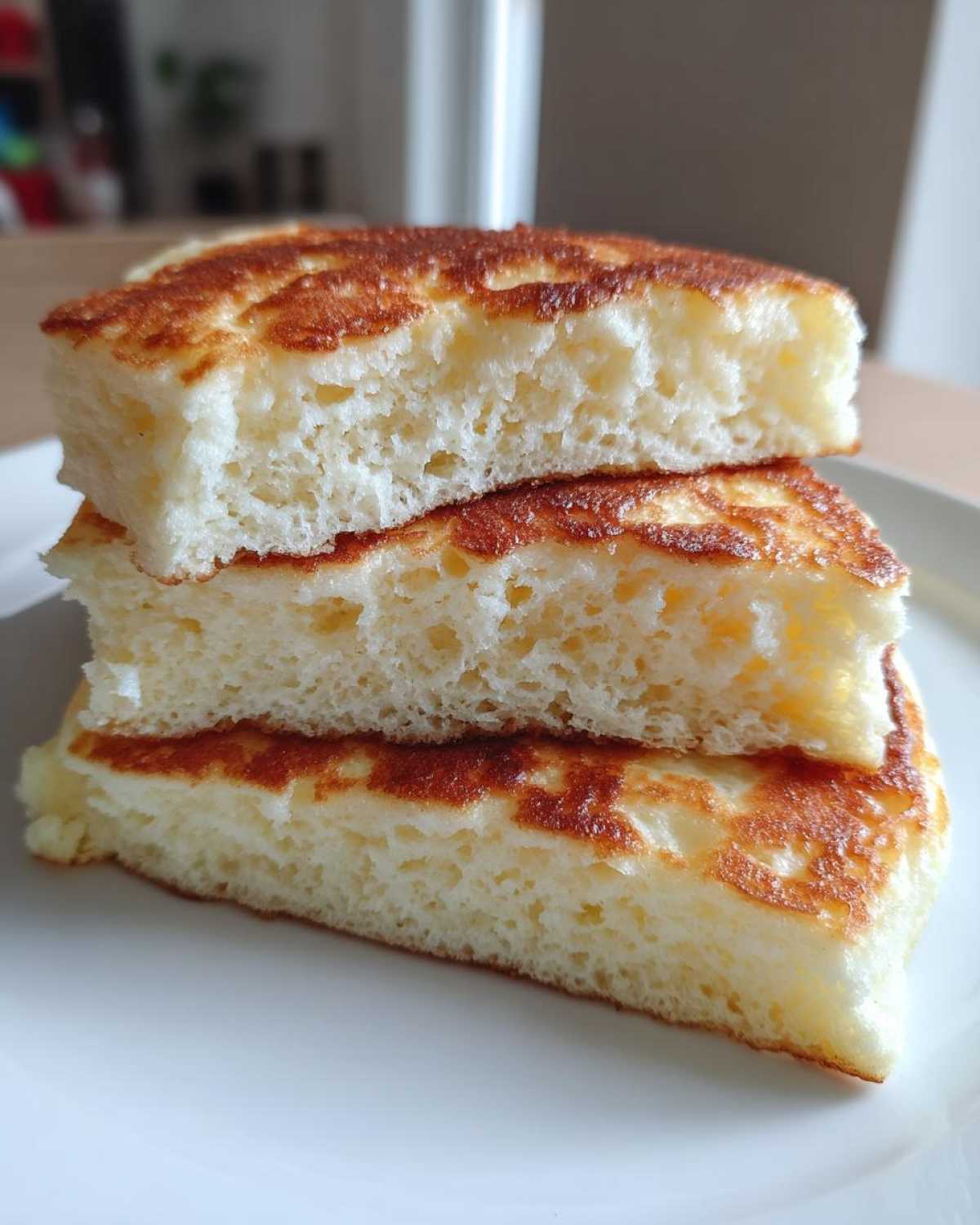 Close-up of three stacked slices showing the incredibly airy and fluffy pancakes interior.