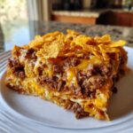 A hearty slice of Dorito Casserole featuring layers of seasoned ground beef, melted cheese, and a crunchy Dorito topping.