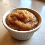Close-up of homemade applesauce, spiced with cinnamon, served in a small white ramekin.