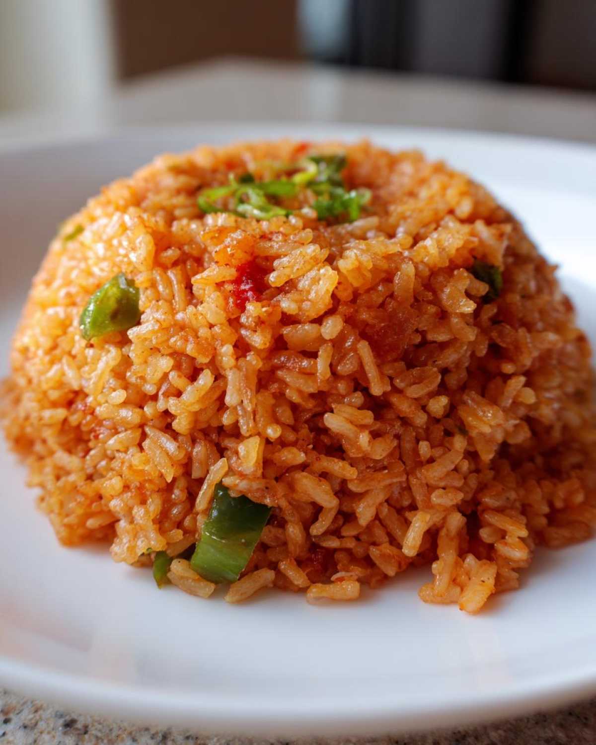 A close-up of a perfectly molded mound of vibrant orange spanish rice garnished with green onions and peppers.