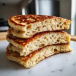 Close-up of three stacked almond flour pancakes showing their fluffy interior texture and golden-brown edges.
