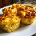 Close-up of four fluffy, golden-brown baked egg bites served on a white plate.