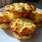 A stack of five golden-brown, fluffy egg bites served on a white plate, ready for breakfast.