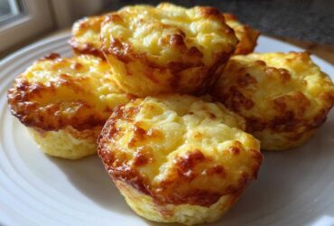 A stack of five golden-brown, fluffy egg bites served on a white plate, ready for breakfast.