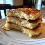 Cross-section view showing the airy, fluffy pancakes stacked three high, glistening with syrup.