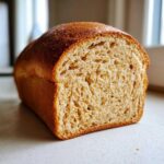 Close-up of a freshly baked whole wheat bread loaf, showing its fluffy, open crumb structure and golden crust.