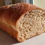 Close-up of a freshly baked loaf of whole wheat bread, showing a soft, airy crumb and a golden-brown crust.