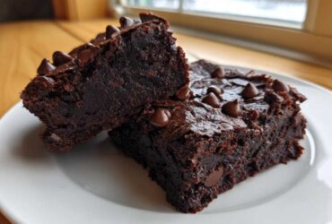 Two fudgy black bean brownies topped with melted chocolate chips served on a white plate.