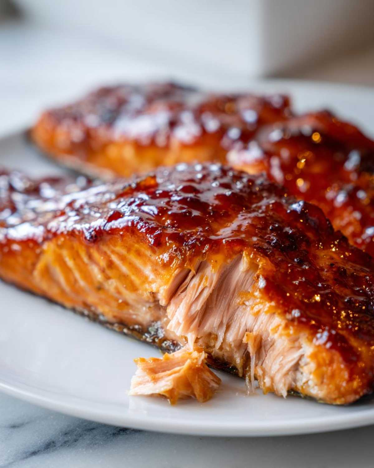 Close-up of a perfectly cooked, glazed salmon steak showing moist, flaky interior texture.