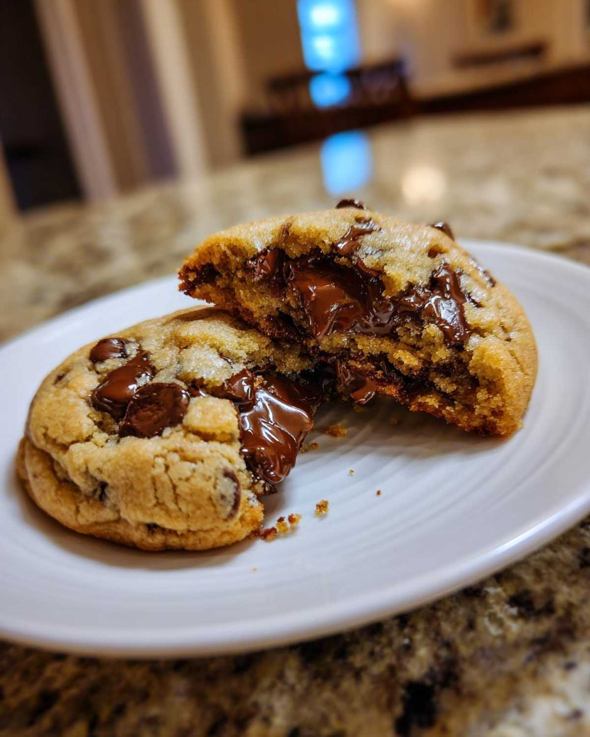 A warm chocolate chip cookie broken in half revealing a molten, gooey chocolate center.
