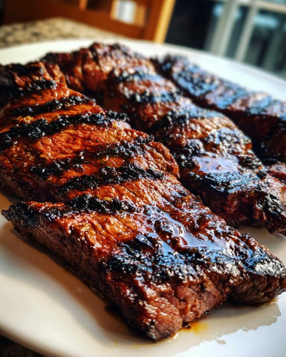 Close-up of perfectly grilled steak strips showing dark char marks, glistening with juices from the carne asada marinade.