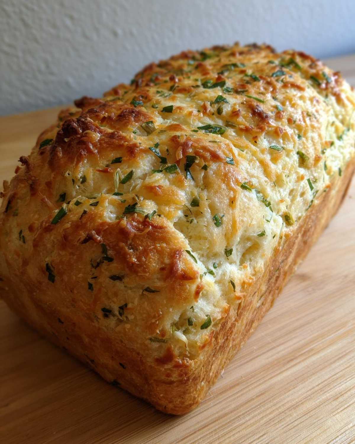 A freshly baked loaf of Italian herb and cheese bread with a golden crust and melted cheese topping.