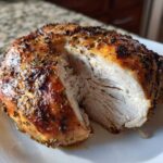 Close-up of a juicy air fryer whole chicken breast cut open, showing perfectly cooked white meat and seasoned, browned skin.