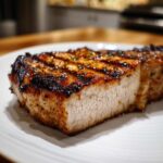 Close-up of a thick, juicy pork chop showing grill marks and a perfectly cooked interior using the marinade for pork chops.