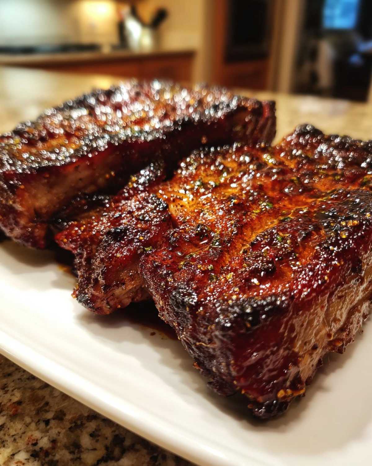 Close-up of three thick, glazed, and perfectly seared pork steak recipe portions on a white plate.