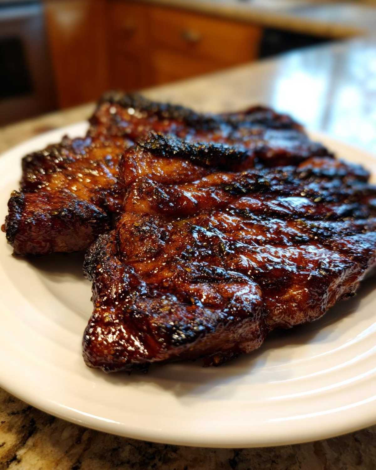 Close-up of three beautifully caramelized and glazed pork steak pieces resting on a white plate.