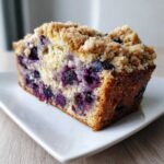 Close-up of a moist slice of blueberry banana bread topped with crunchy streusel.