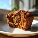 Close-up of a moist bran muffins half eaten, showing the crumb texture and raisins inside.