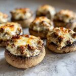 Close-up of baked sausage stuffed mushrooms topped with melted, browned cheese.