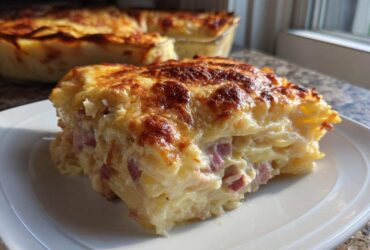 A thick slice of creamy scalloped potatoes and ham bake with a golden-brown cheesy crust.