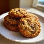 A stack of freshly baked, soft chewy oatmeal cookie cookies with chocolate chips on a white plate.