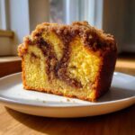 A moist slice of marbled sour cream coffee cake featuring a rich cinnamon swirl and crunchy streusel topping.