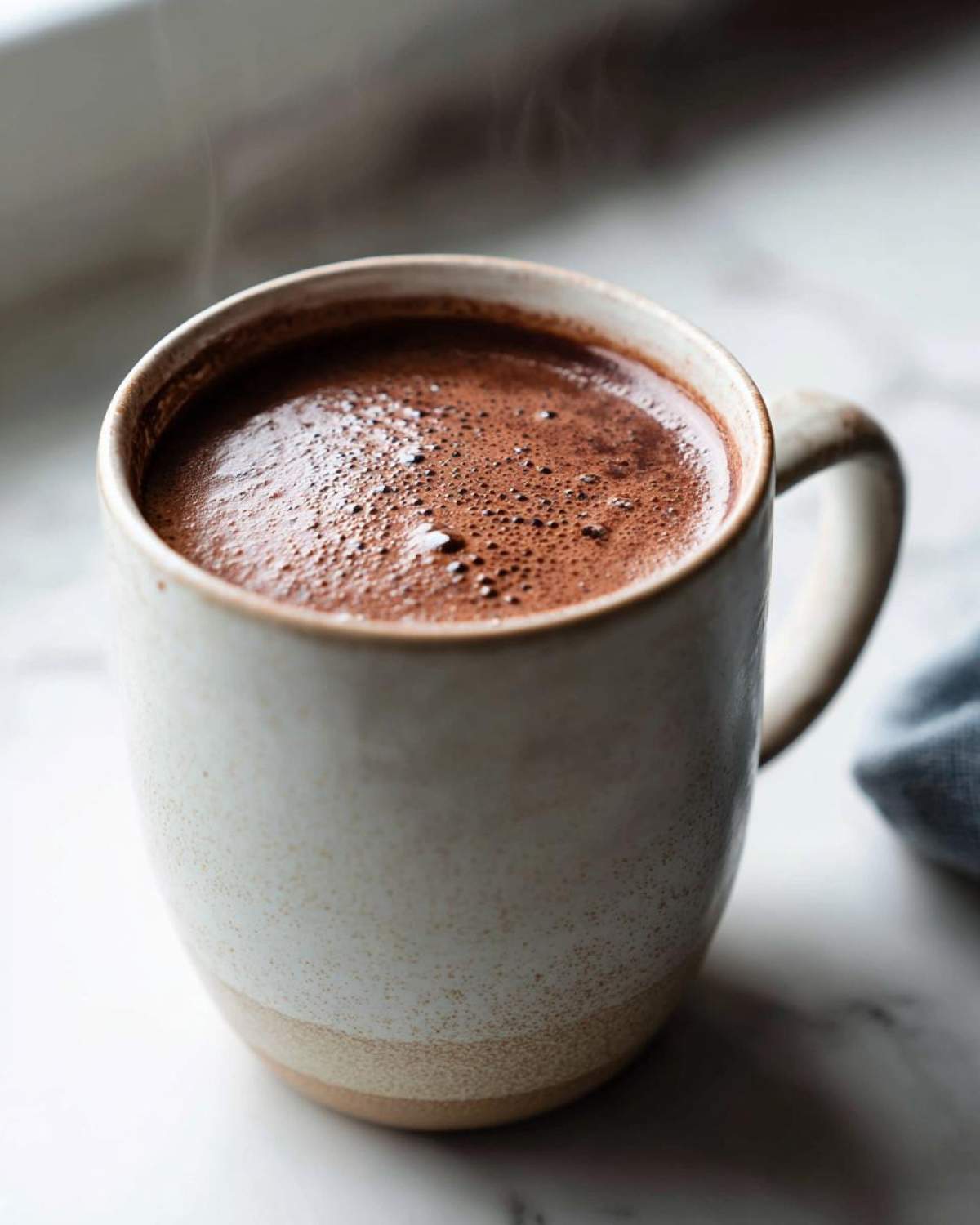 Close-up of a steaming mug filled with rich, frothy hot cocoa made from homemade hot cocoa mix.