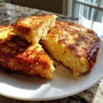 Close-up of thick, golden-brown easy french toast slices stacked on a white plate, showing a fluffy interior.