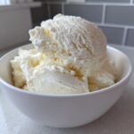Close-up of creamy vanilla protein ice cream scoops served in a simple white bowl.