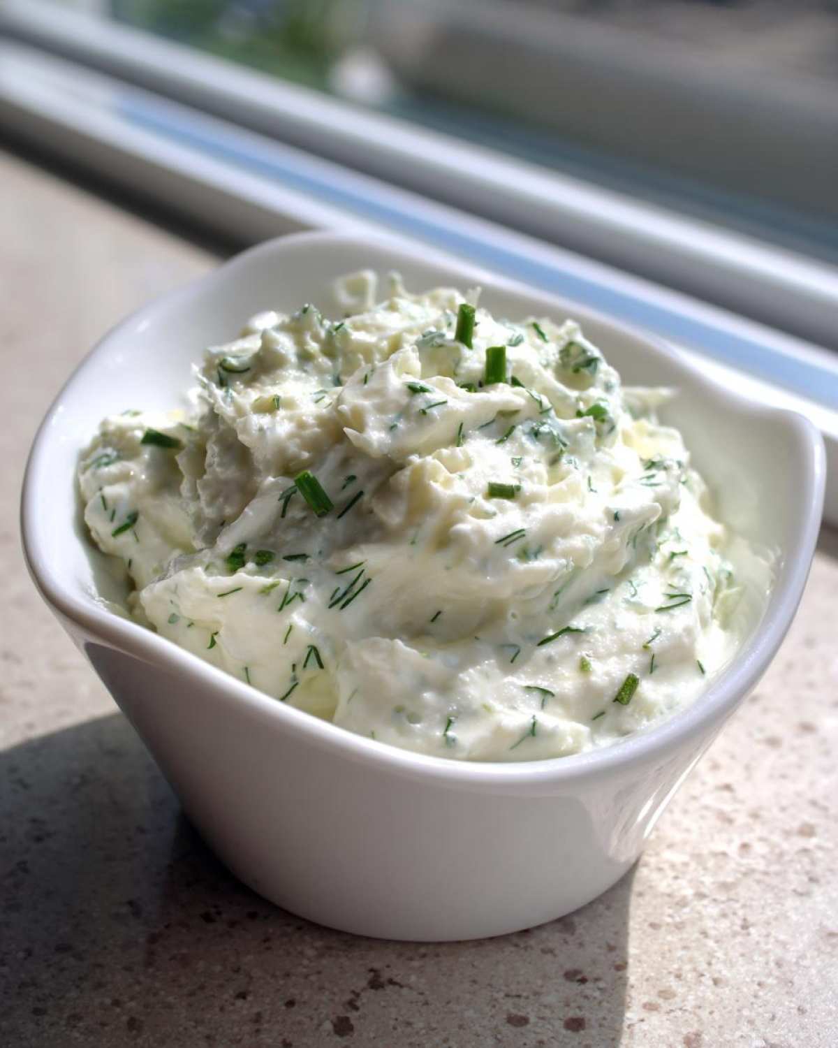 Close-up of thick 5-Minute Greek Yogurt Ranch Dip topped with fresh chives in a small white serving bowl.