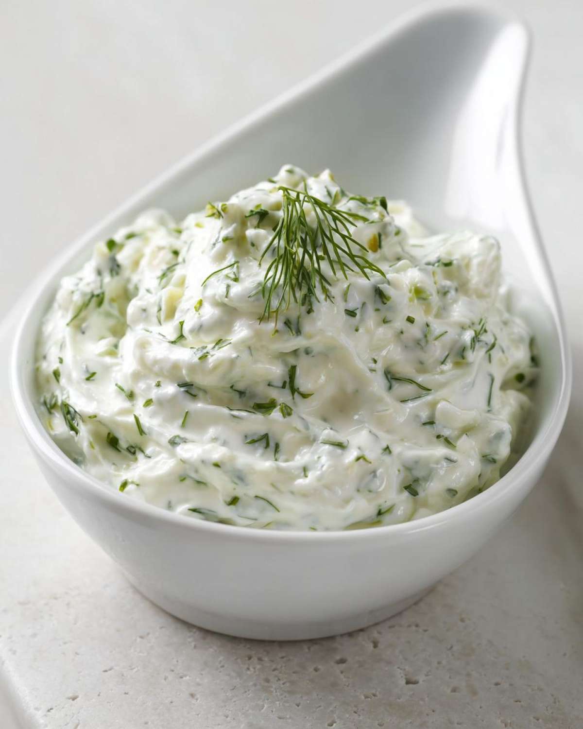 Close-up of creamy 5-Minute Greek Yogurt Ranch Dip, mixed with green herbs and topped with fresh dill.