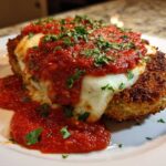 A close-up of crispy Air Fryer Chicken Parmesan topped with melted mozzarella and marinara sauce, garnished with parsley.