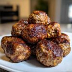 A close-up stack of perfectly browned Air Fryer Italian Meatballs piled high on a white plate.