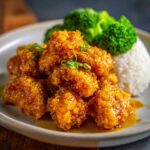 Close-up of crispy, glazed Air Fryer Orange Chicken served with white rice and steamed broccoli florets.