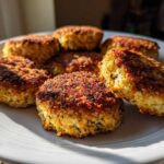 A plate holding six golden-brown, crispy Air Fryer Salmon Patties, perfectly cooked.