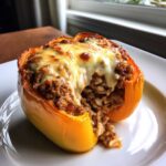 Close-up of a bright yellow Air Fryer Stuffed Bell Peppers overflowing with savory meat and rice filling, topped with melted cheese.